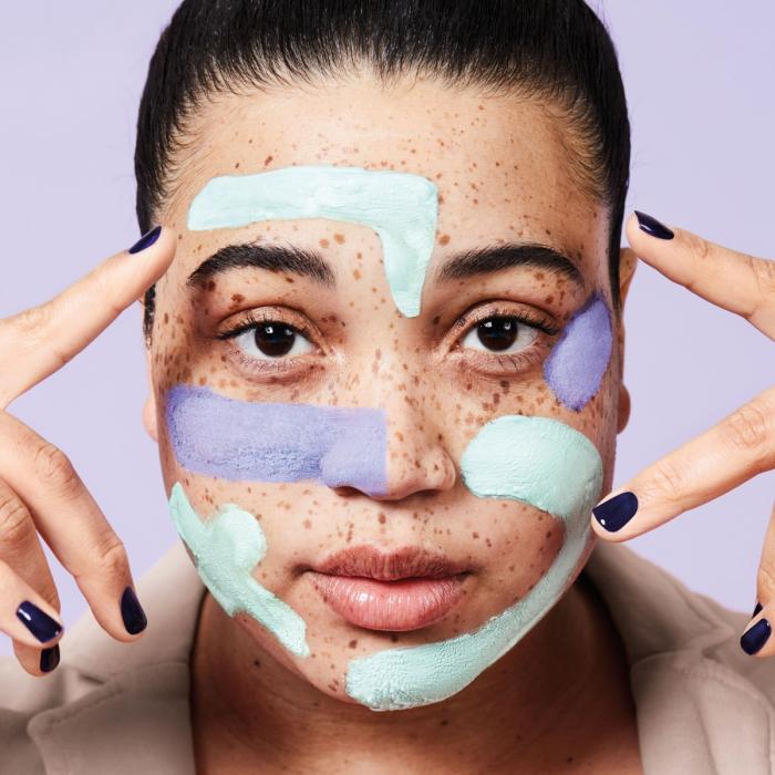 Dark haired model with freckles and pastel coloured face mask 