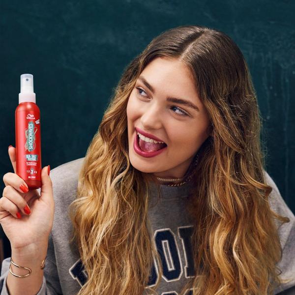 Model smiling with long hair and can of hairspray